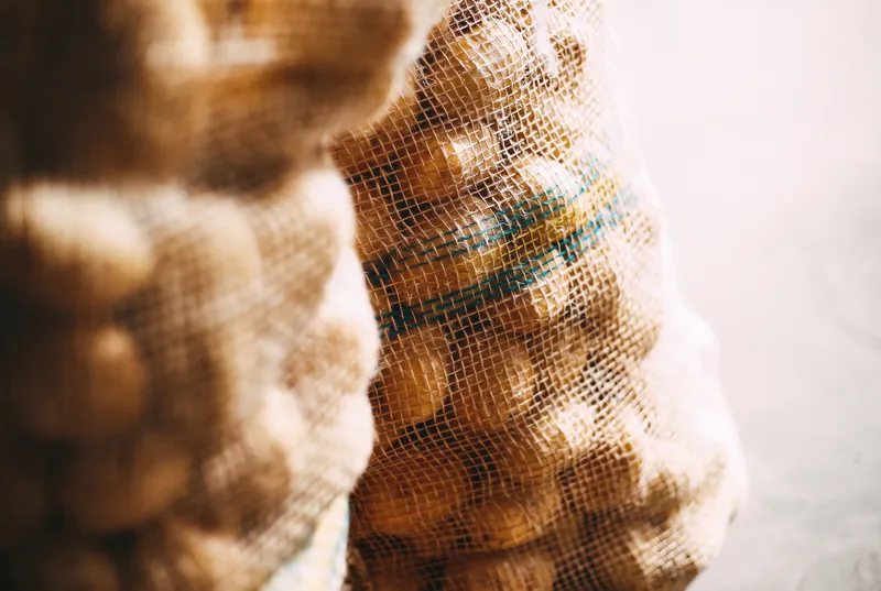 Detalhe da trama de sacaria com batatas e faixa verde